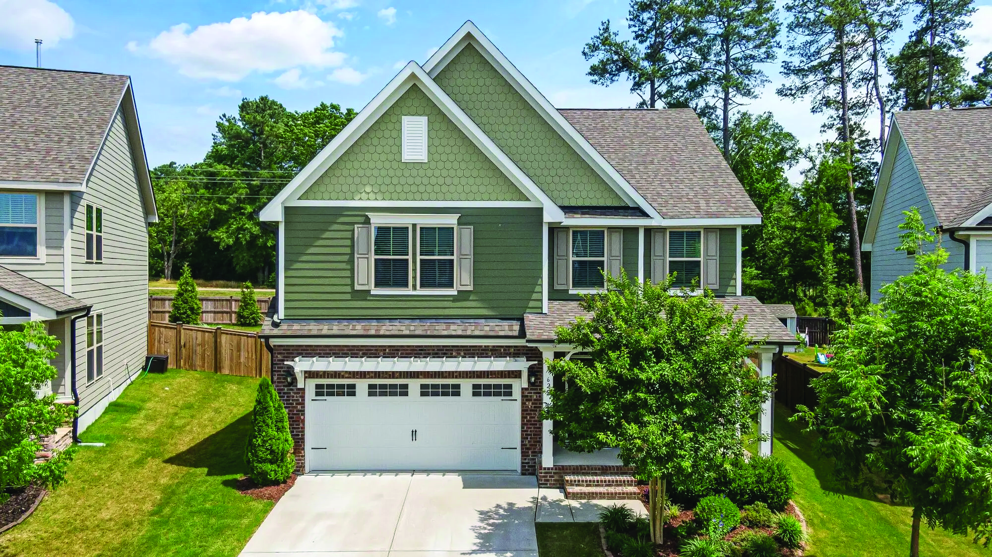 A two-storey home with a double garage on a tree-lined street.